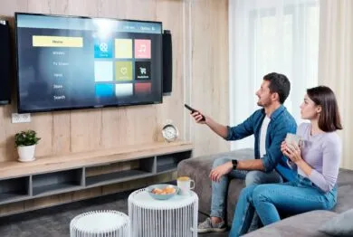 Young couple having tea while going to watch something on plasma tv panel