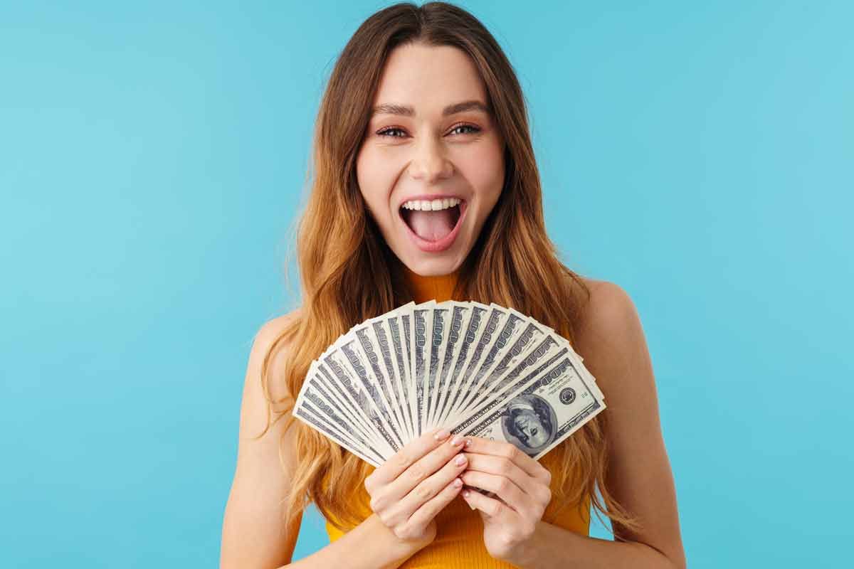 A happy woman holding U.S. cash, representing checks in the mail.