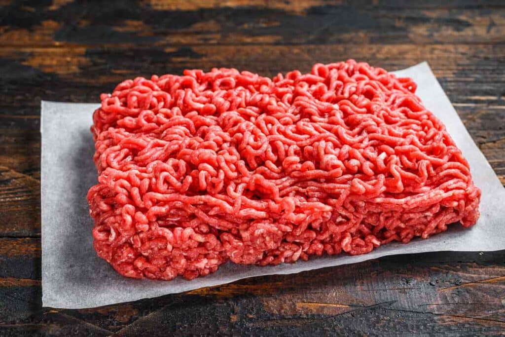 Raw ground beef on parchment paper on a kitchen counter, representing the ground beef recall.