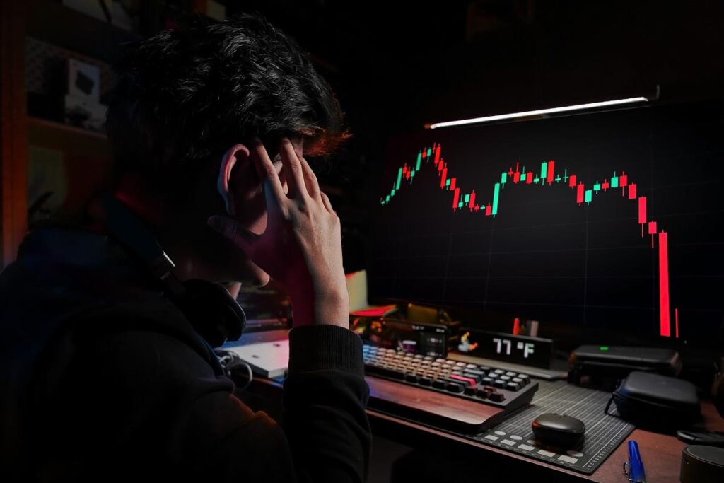 A stressed male looking at a computer screen of his crypto plummeting, representing the "Hawk Tuah" lawsuit.