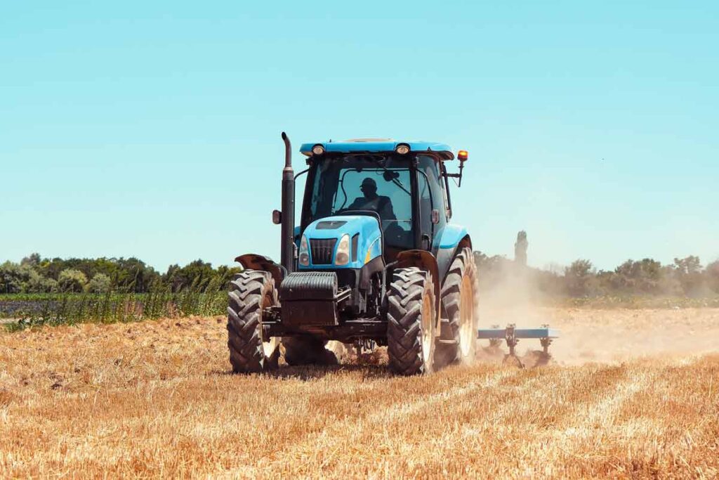A farmer driving a tractor in a field, representing the SunWest settlement.