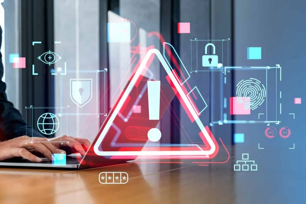 A person typing on a laptop with a warning symbol overlay, representing the Nucor data breach class action settlement.