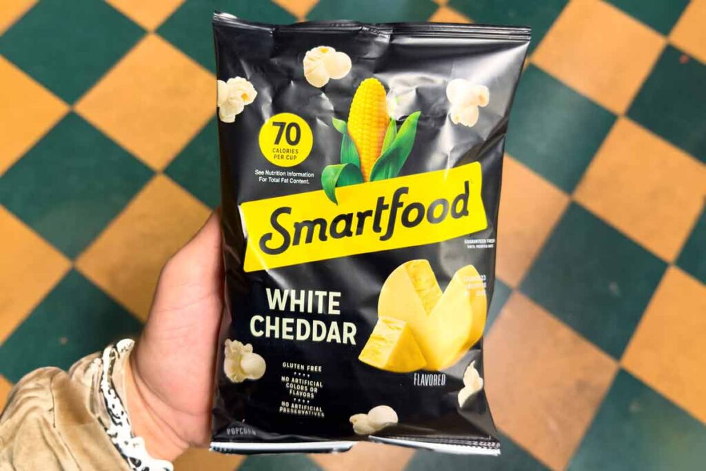 Close up of a hand holding Smartfoods white cheddar popcorn, representing the Smartfoods class action.