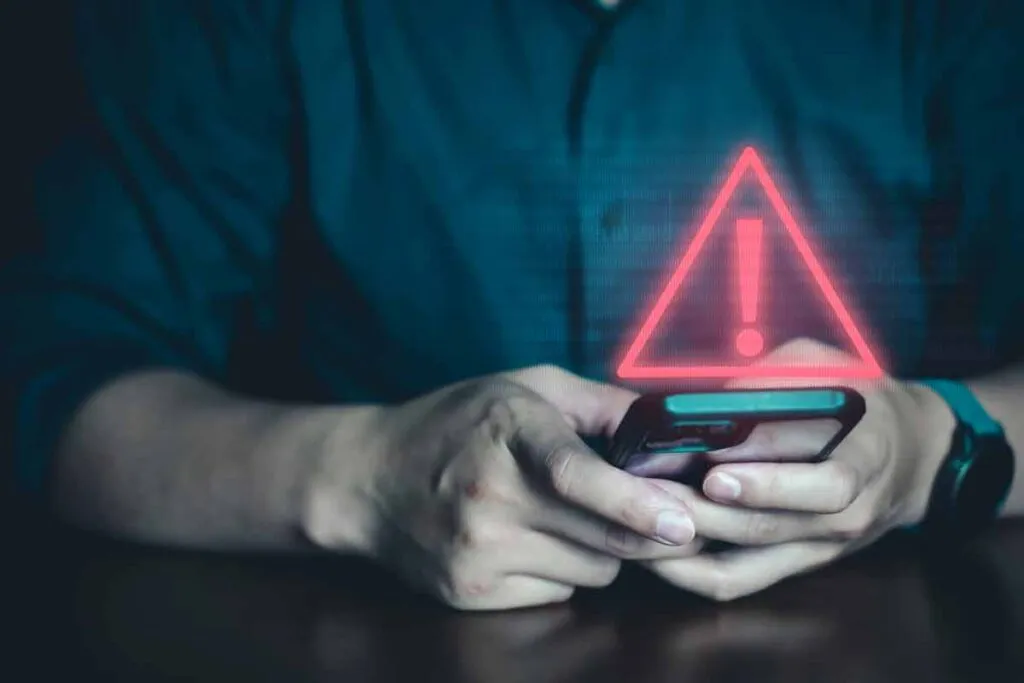 Close up of a man using a smartphone with a warning symbol overlay, representing the API Financial Solutions settlement.