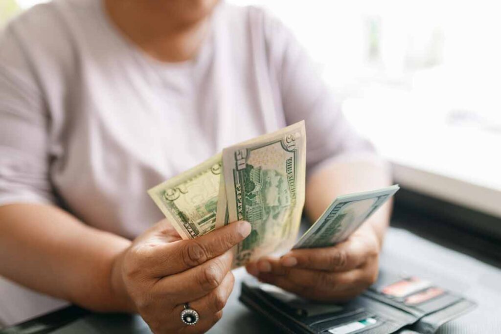 A woman holding U.S. cash, representing recent class action rebates.