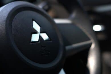 Close up of Mitsubishi logo on a steering wheel, representing the Mitsubishi settlement.
