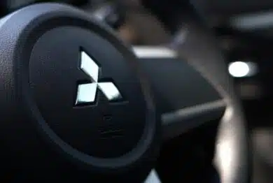 Close up of Mitsubishi logo on a steering wheel, representing the Mitsubishi settlement.