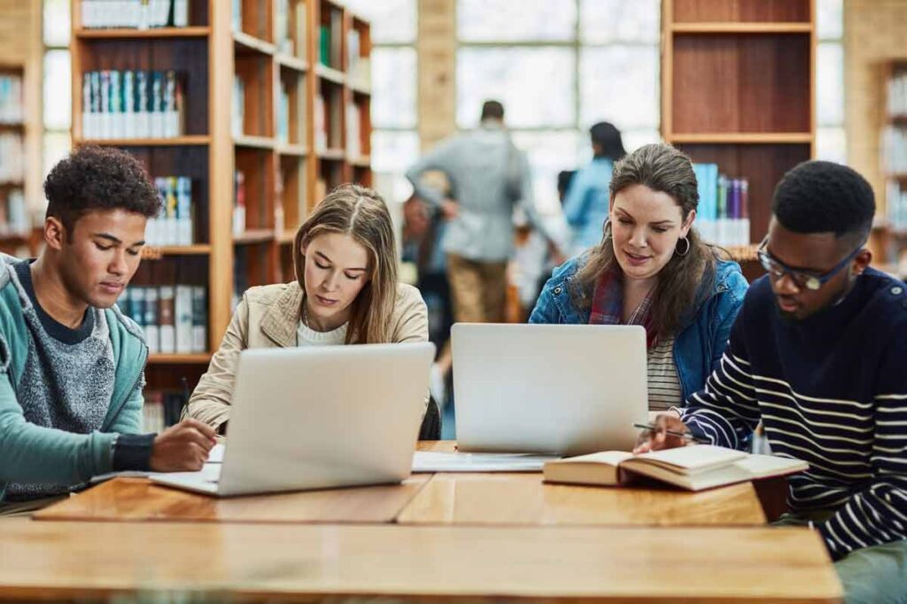 College students using laptops in a library, representing the Lansing Community College settlement.