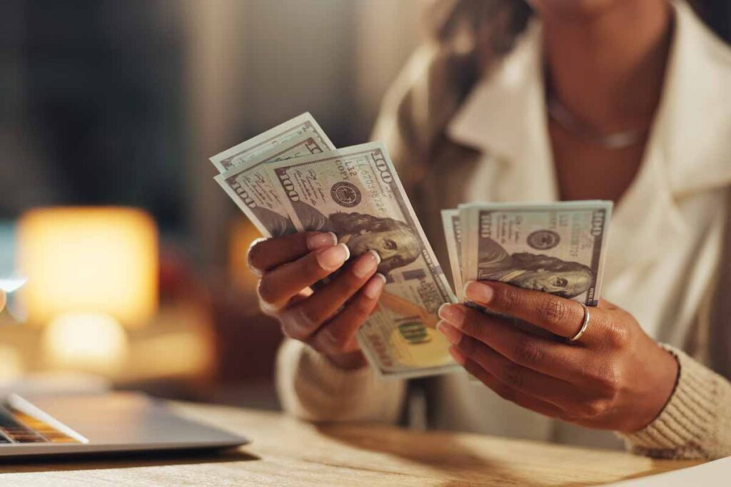 Close up of a woman's hands counting cash, representing FTC refunds.