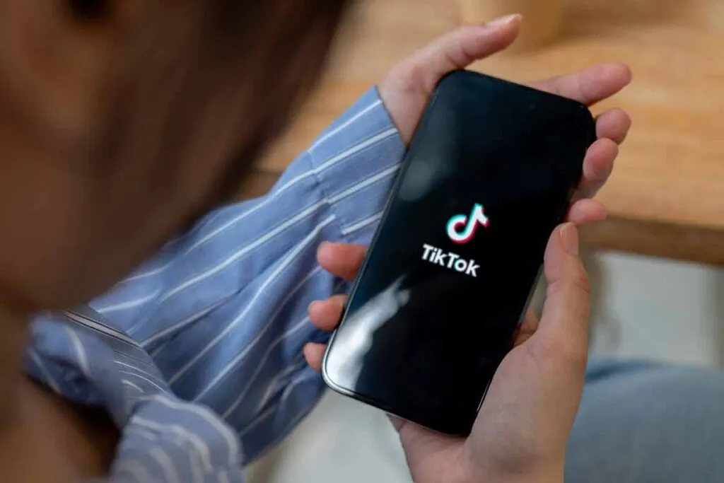 Close up of hands holding a smartphone with the TikTok logo displayed, representing the TikTok class action.