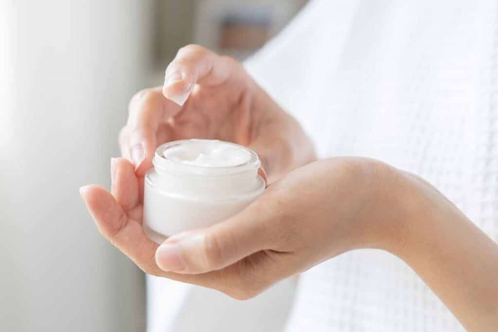 Close up of hand holding face moisturizer, representing the beauty class actions, recall and settlement.