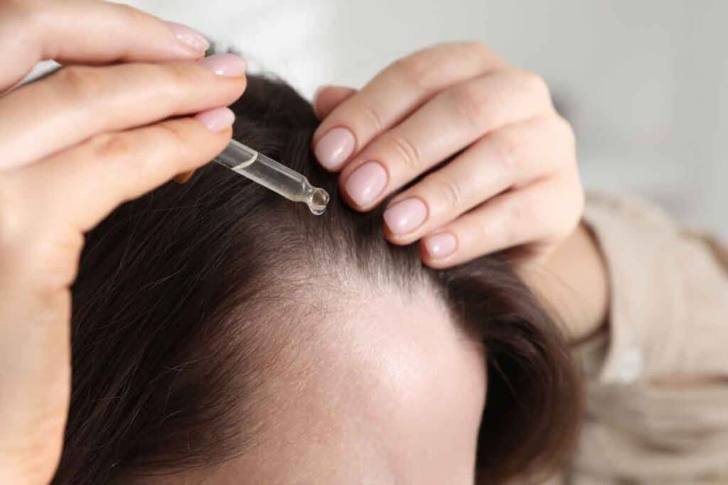 Close up of woman putting oil in her hair, representing the Mielle Organics class action.