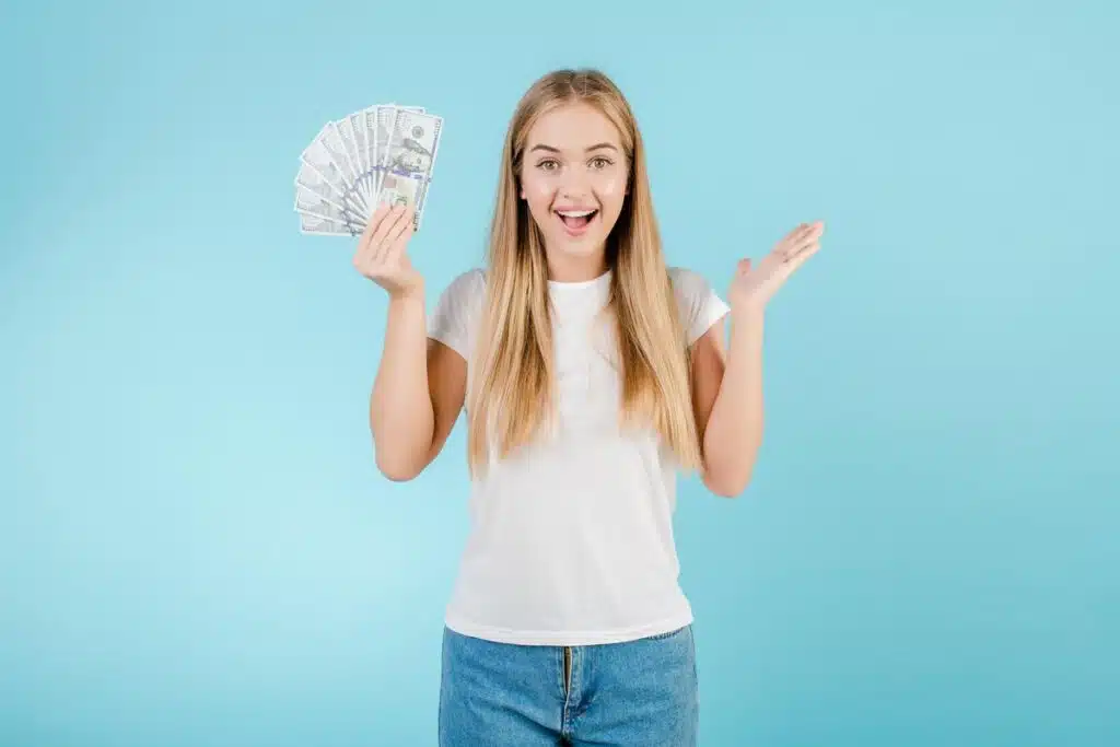 An excited woman holding U.S. cash, representing class action rebates for January 2025.