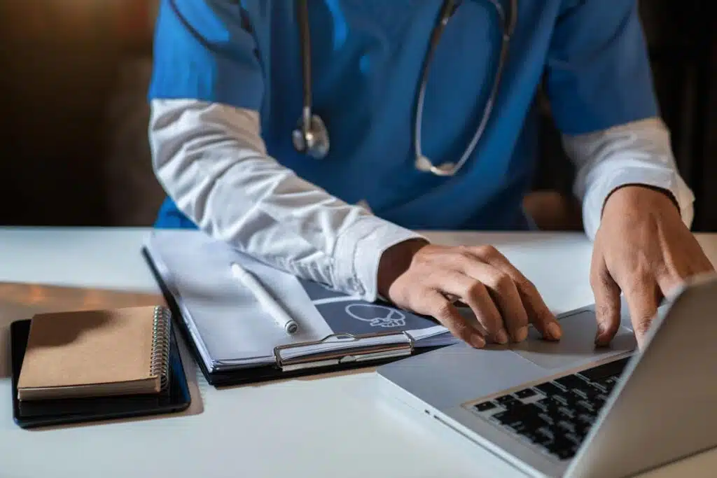 A medical professional typing on a laptop, representing the Mulkay Cardiology Consultants settlement.