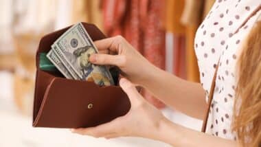 Close up of a woman pulling cash out of a wallet, representing FTC refunds for December 2024.