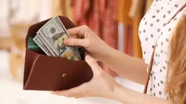 Close up of a woman pulling cash out of a wallet, representing FTC refunds for December 2024.