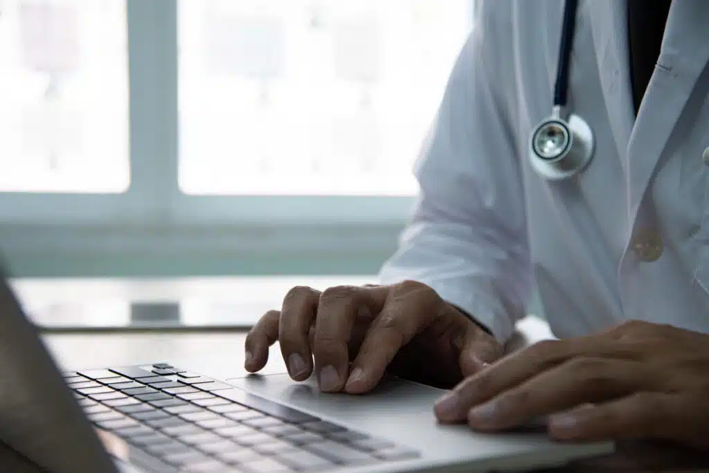 Close up of a doctor typing on a laptop, representing the Eskenazi Health settlement.