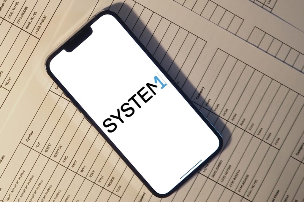 System1 logo displayed on a smartphone screen, representing the System1 settlement.