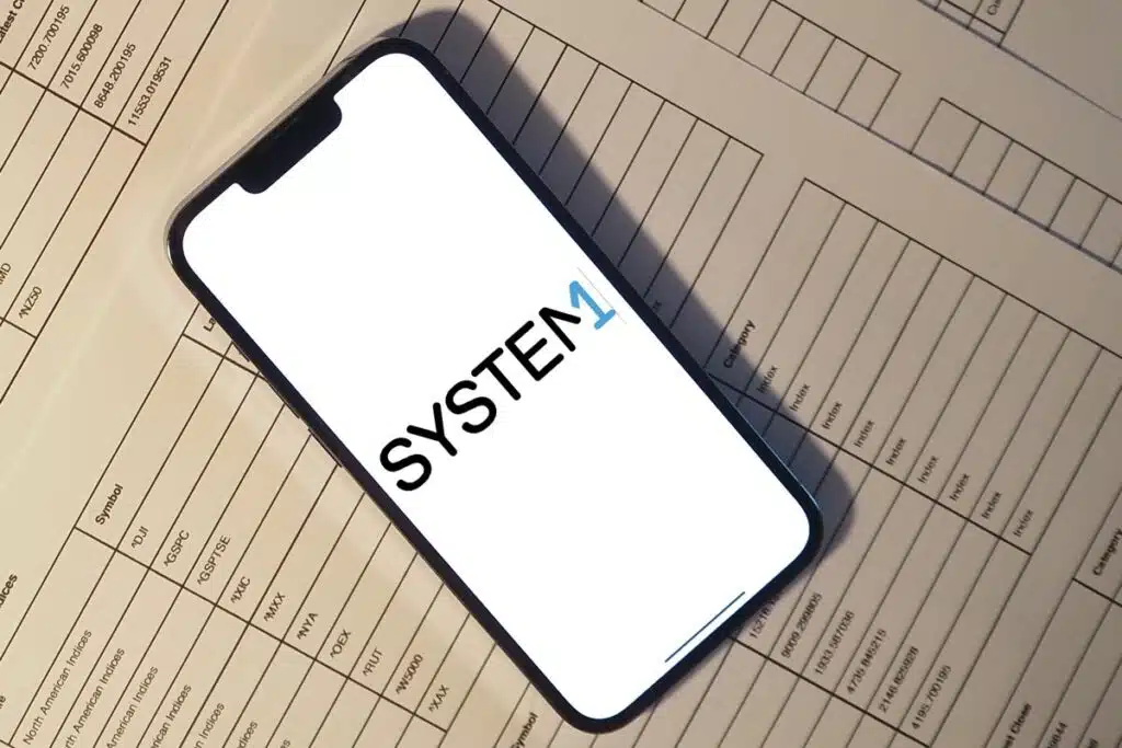 System1 logo displayed on a smartphone screen, representing the System1 settlement.