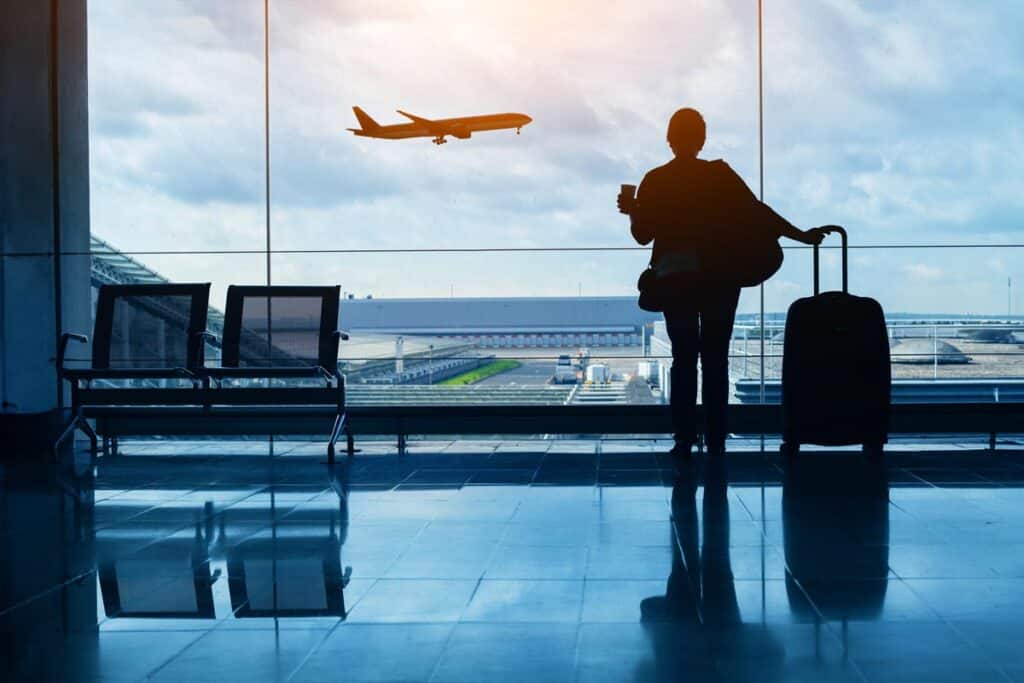 Silhouette of a person watching a plan take off from inside an airport, representing airline lawsuits.