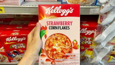 A hand holding Kellogg's strawberry corn flakes cereal, representing the Kellogg's class action.