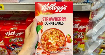A hand holding Kellogg's strawberry corn flakes cereal, representing the Kellogg's class action.