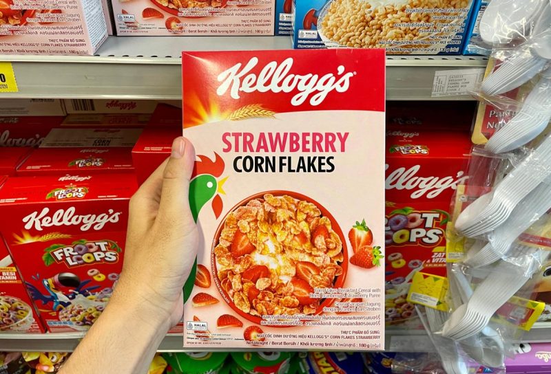 A hand holding Kellogg's strawberry corn flakes cereal, representing the Kellogg's class action.
