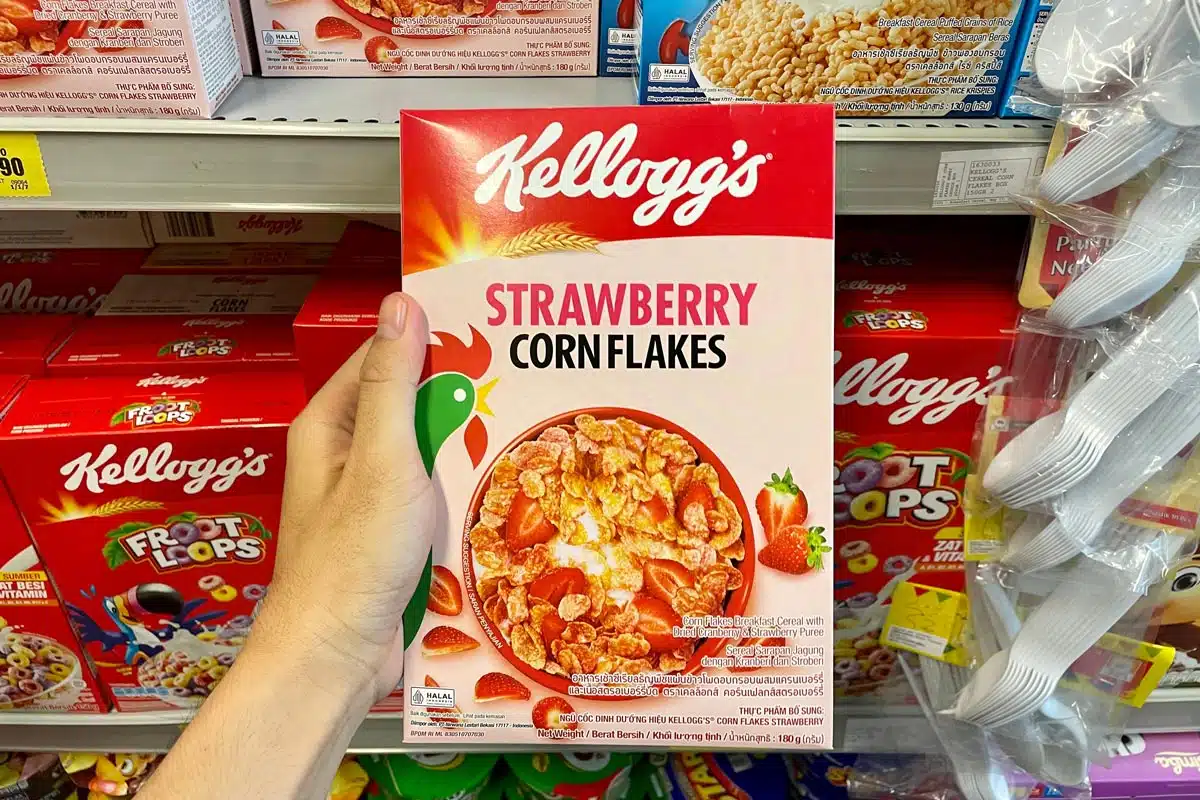 A hand holding Kellogg's strawberry corn flakes cereal, representing the Kellogg's class action.