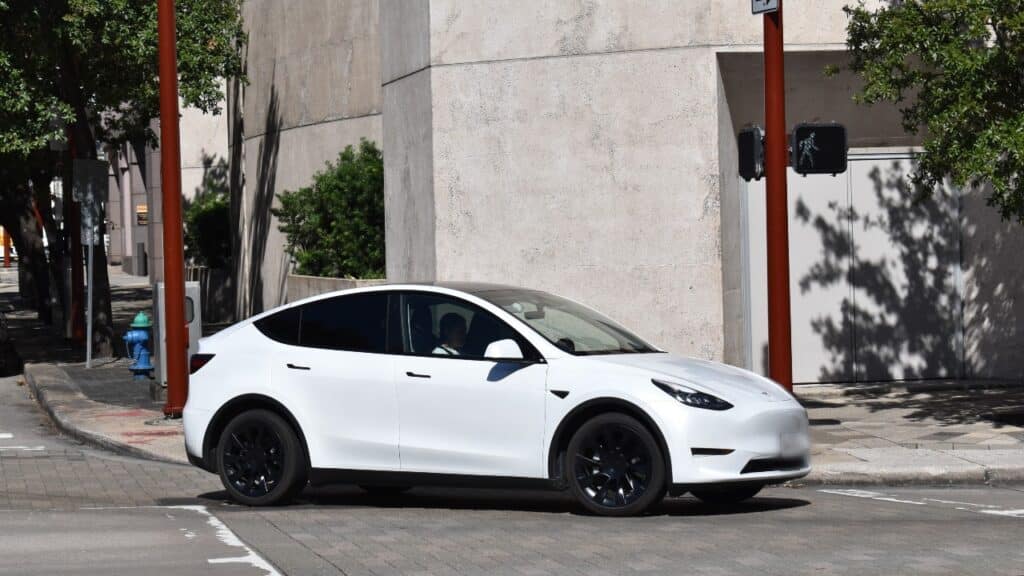 A white Tesla Model 3 driving on a road, representing the Tesla recall.