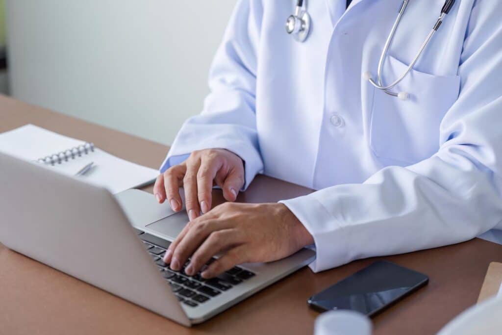 Close up of a doctor typing on a laptop, representing the MU Health Care settlement.