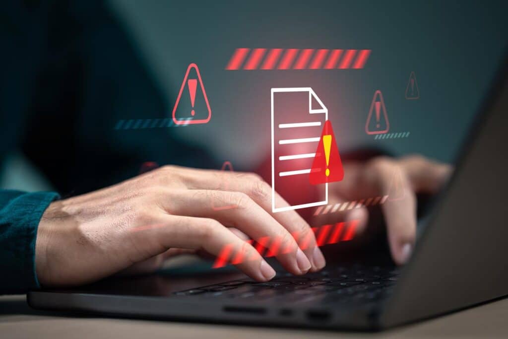 Hands typing on a laptop with a warning symbol, data representation overlay, representing the Vi settlement.