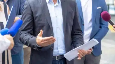 whistleblower holding confidential document and giving a statement to journalists at news conference