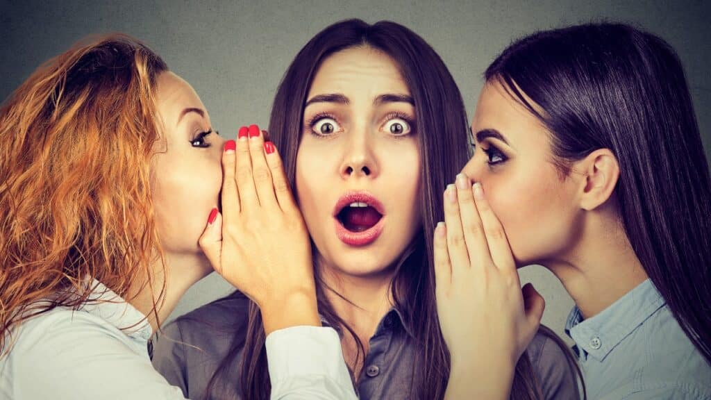Three young women telling whispering a secret gossip each other in the ear