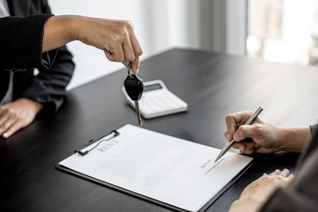 Close up of keys being handed to a customer as they sign a rental agreement, representing the Greystar lawsuit.