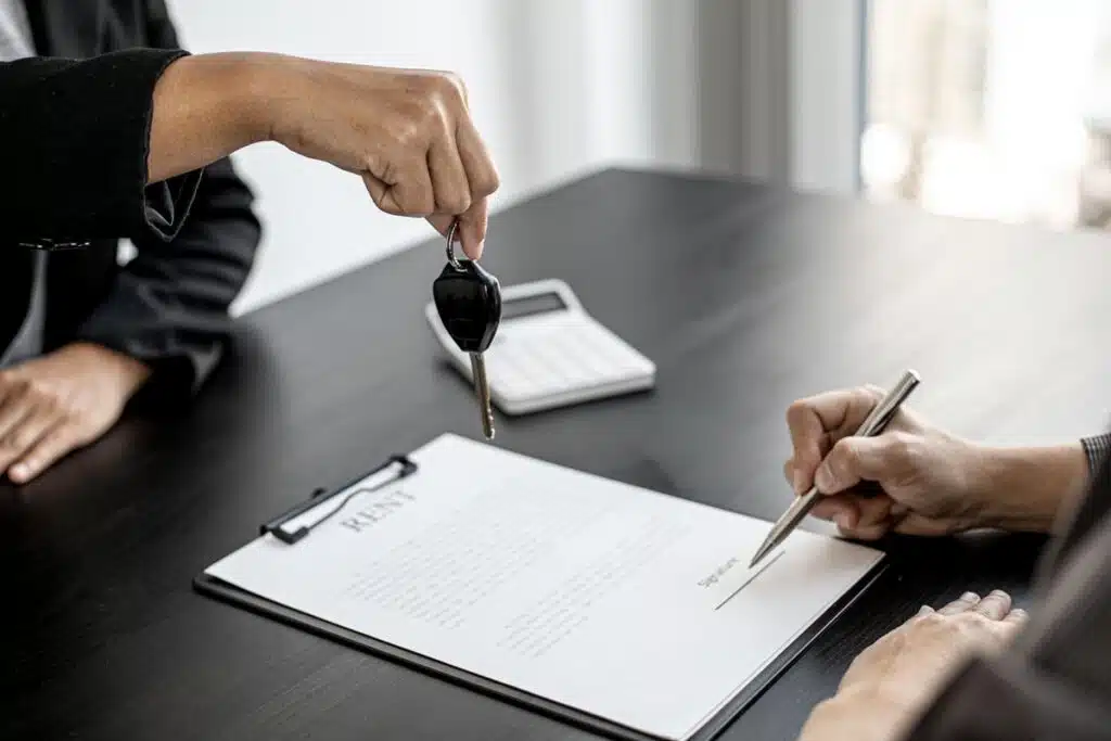 Close up of keys being handed to a customer as they sign a rental agreement, representing the Greystar lawsuit.