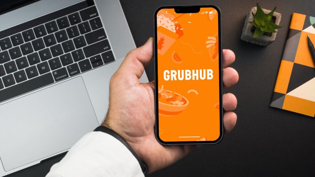 Man holding a smartphone with GrubHub food ordering and delivery app on the screen.