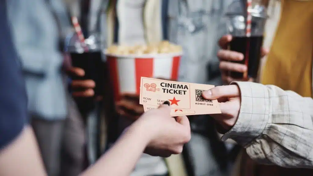 Unrecognizable people giving tickets for movie to cinema worker to enter hall
