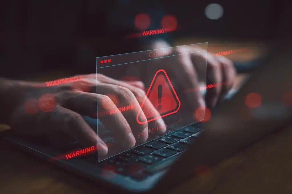 Close up of hands typing on a laptop with a warning symbol overlay, representing the District of Columbia Health Benefit Exchange Authority settlement.