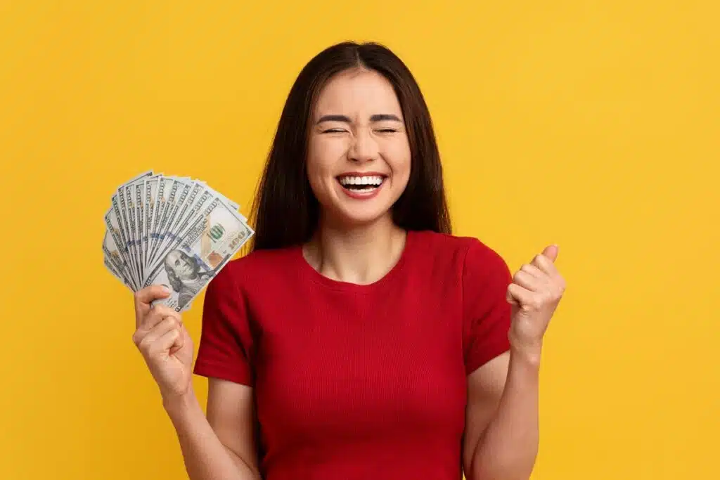 An excited woman holding U.S. cash, representing January rebates.