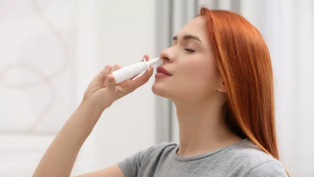 Woman using nasal spray at home