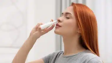 Woman using nasal spray at home
