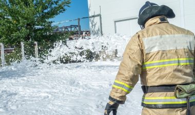 The firefighter is wearing protective clothing and a helmet. Foam for extinguishing the fire. Foam fire extinguishing technology.