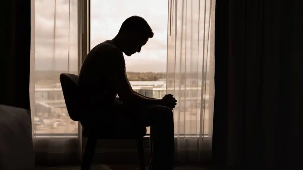 thoughtful man in a dark room with head down