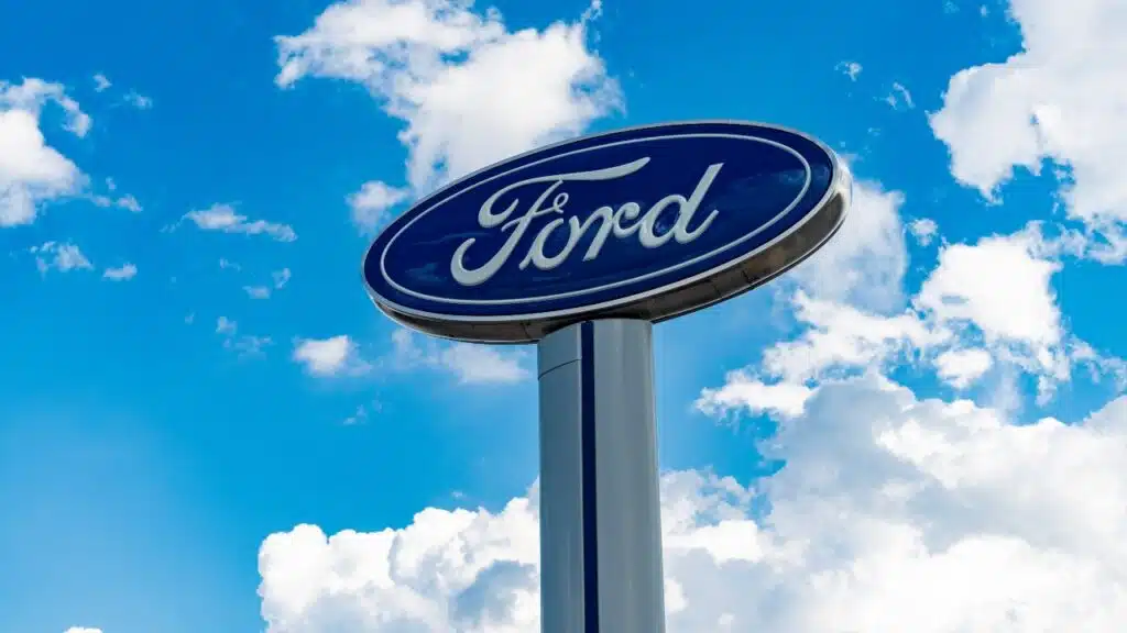 Ford logo sign against blue cloudy sky.