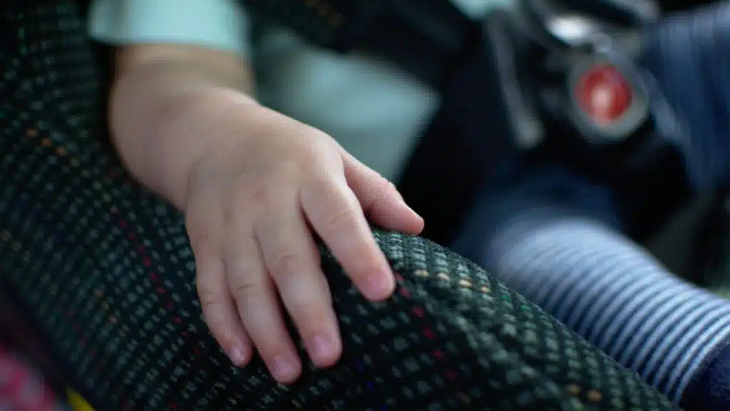 Baby place his hand on the car seat and sit calm. Baby sit in rear facing car seat.
