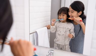 Mother helping toddler brush teeth