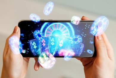 online casino, in a man's hand a smartphone with playing cards, roulette and chips, black-neon background.