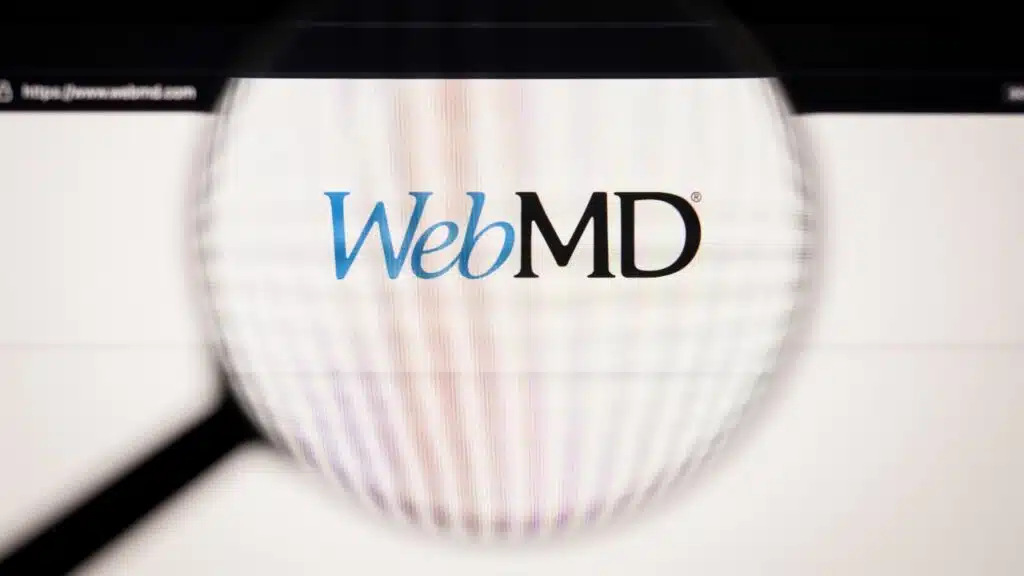 WebMD company logo on a website, seen on a computer screen through a magnifying glass.