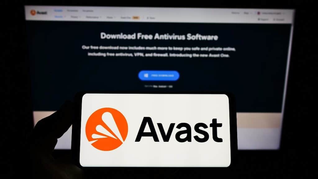 Person holding smartphone with logo of cyber security company Avast Software s.r.o. on screen in front of website.