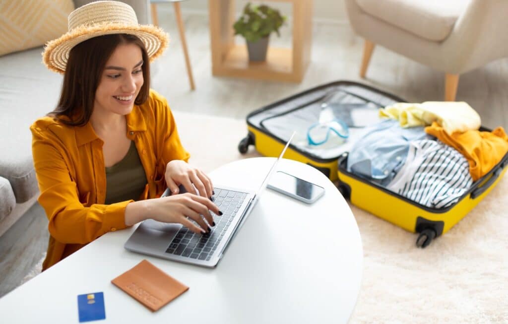 Happy young woman planning vacation travel with laptop pc